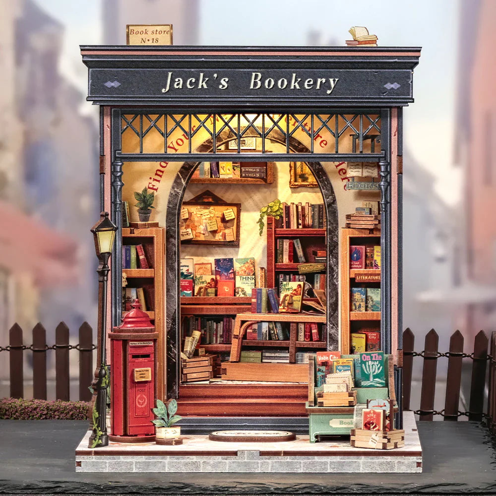Jake's Bookery DIY book nook kit. Miniature wooden bookstore diorama with shelves of books, ladder, vintage details, and warm LED lighting. Designed to slide between books on a bookshelf.