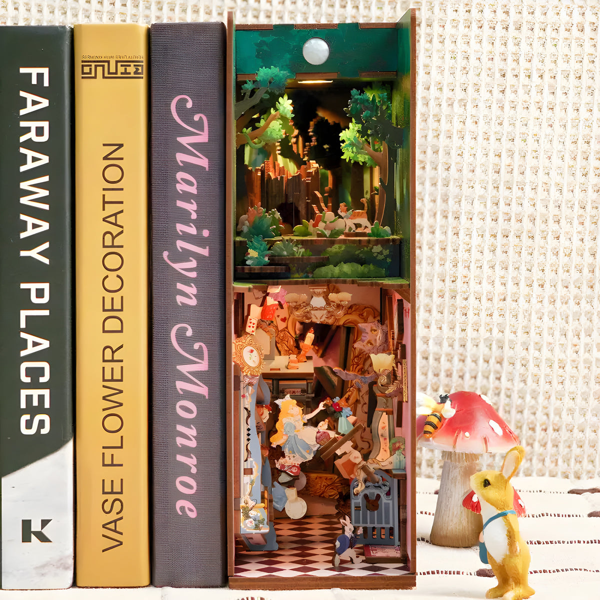 Alice in Wonderland DIY book nook kit. Miniature wooden fantasy diorama with iconic tea party details, playing cards, garden elements, and warm LED lighting. Designed to slide between books on a bookshelf.