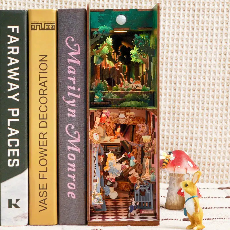 Alice in Wonderland DIY book nook kit. Miniature wooden fantasy diorama with iconic tea party details, playing cards, garden elements, and warm LED lighting. Designed to slide between books on a bookshelf.