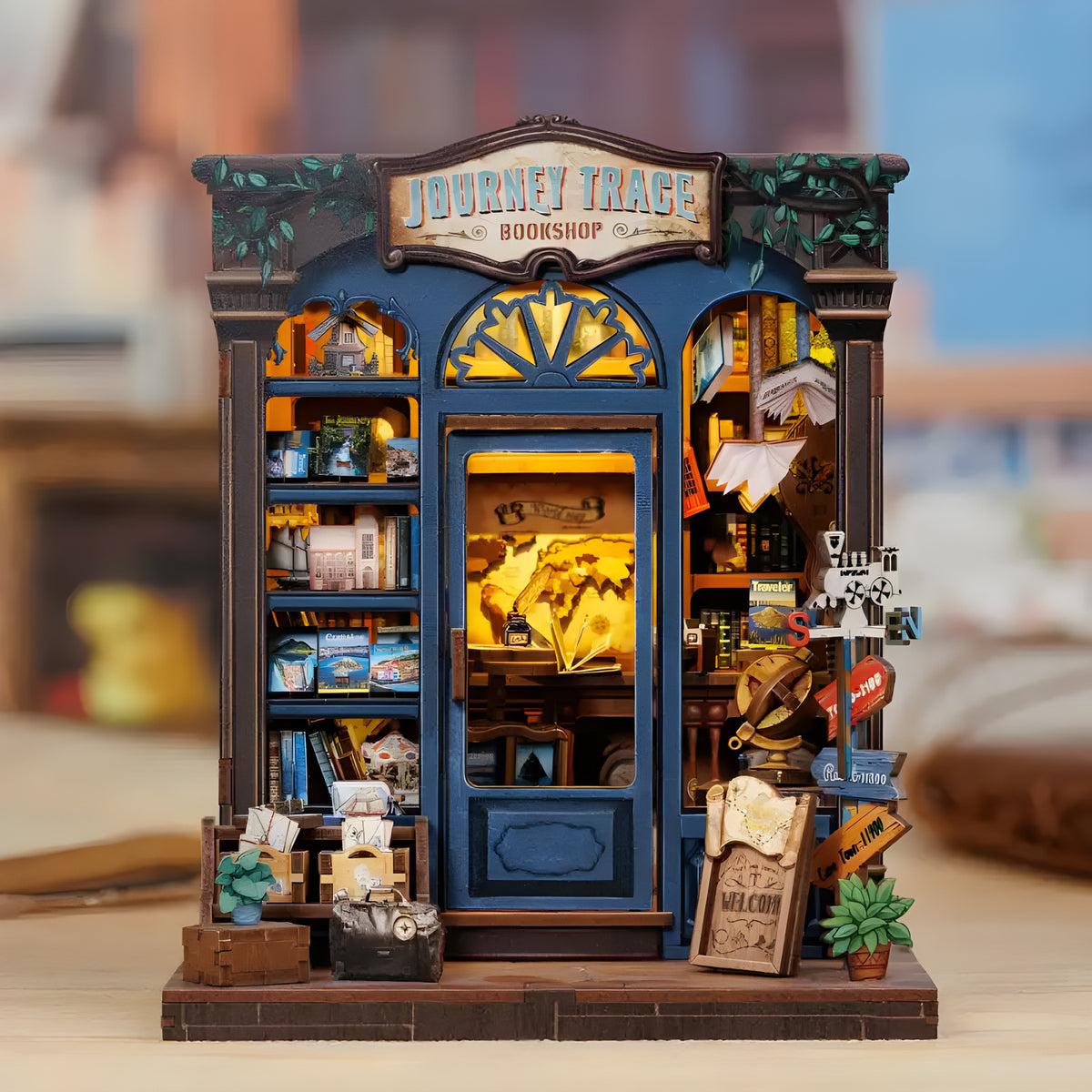 Journey Trace Bookshop DIY book nook kit. Miniature wooden travel-themed bookstore diorama with maps, vintage trunks, books, and warm LED lighting. Designed to slide between books on a bookshelf.