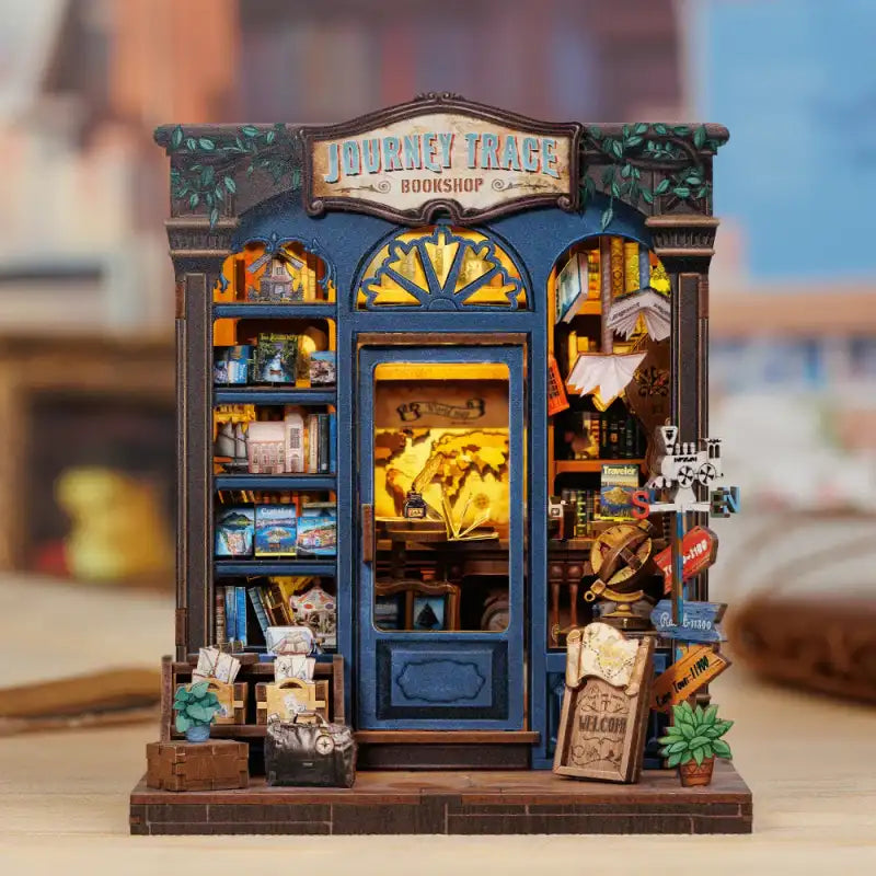 Journey Trace Bookshop DIY book nook kit. Miniature wooden travel-themed bookstore diorama with maps, vintage trunks, books, and warm LED lighting. Designed to slide between books on a bookshelf.