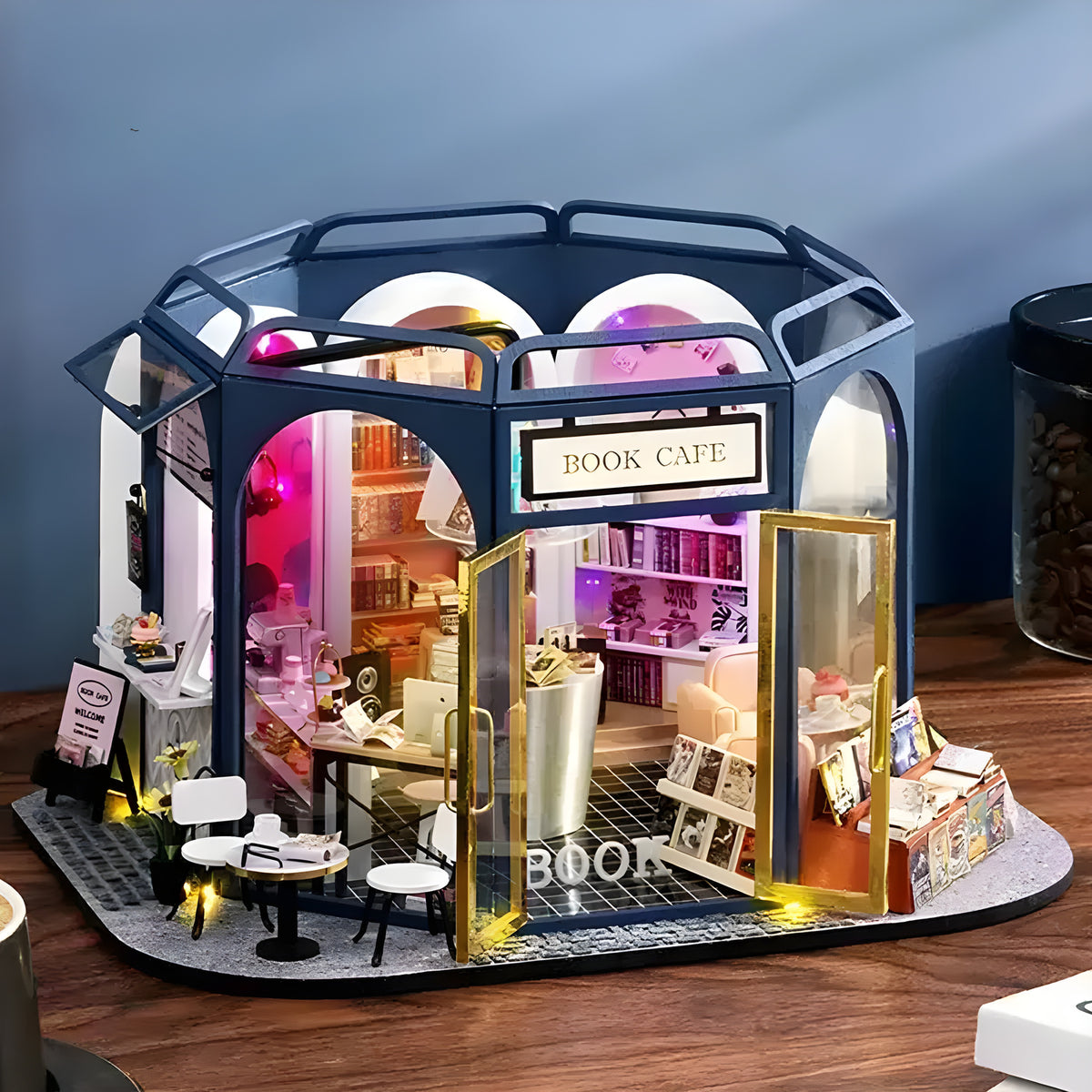 Literary Cafe DIY miniature house kit. Wooden model of a cozy cafe combined with bookshop, full of books, vintage seating, warm coffee details, and LED lighting.
