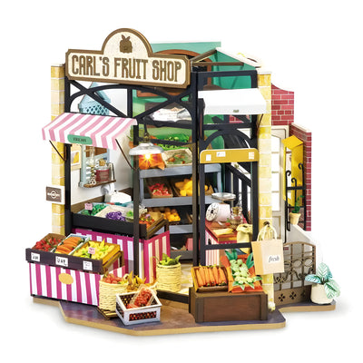 Carl's Fruit Shop DIY miniature house kit. Wooden model of a colorful fruit market with crates of produce, awning, vintage signage, and warm LED lighting.