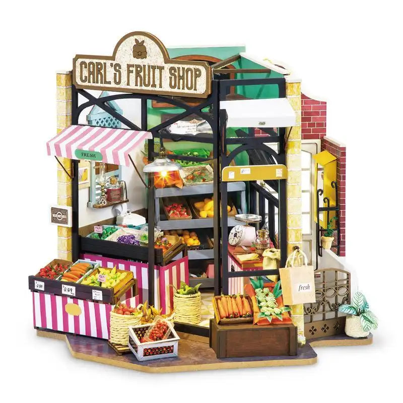 Carl's Fruit Shop DIY miniature house kit. Wooden model of a colorful fruit market with crates of produce, awning, vintage signage, and warm LED lighting.