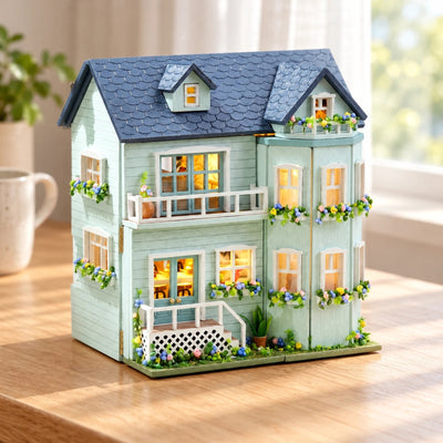 Mint Villa DIY miniature house kit on a wooden table, mint clapboard house with lit windows and flower boxes